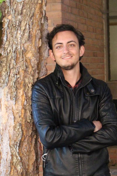 A young man standing next to a tree