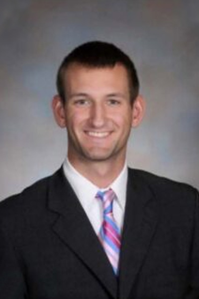 A professional three quarters portrait of a young man in a suit smiling