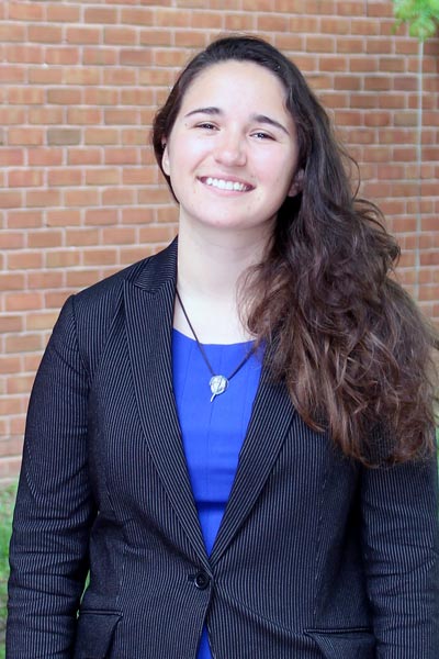 A smiling young woman standing outside in an office building