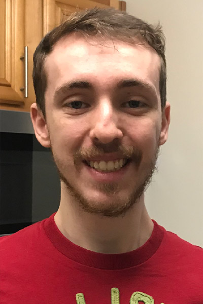 A young man with a light beard smiling in his office