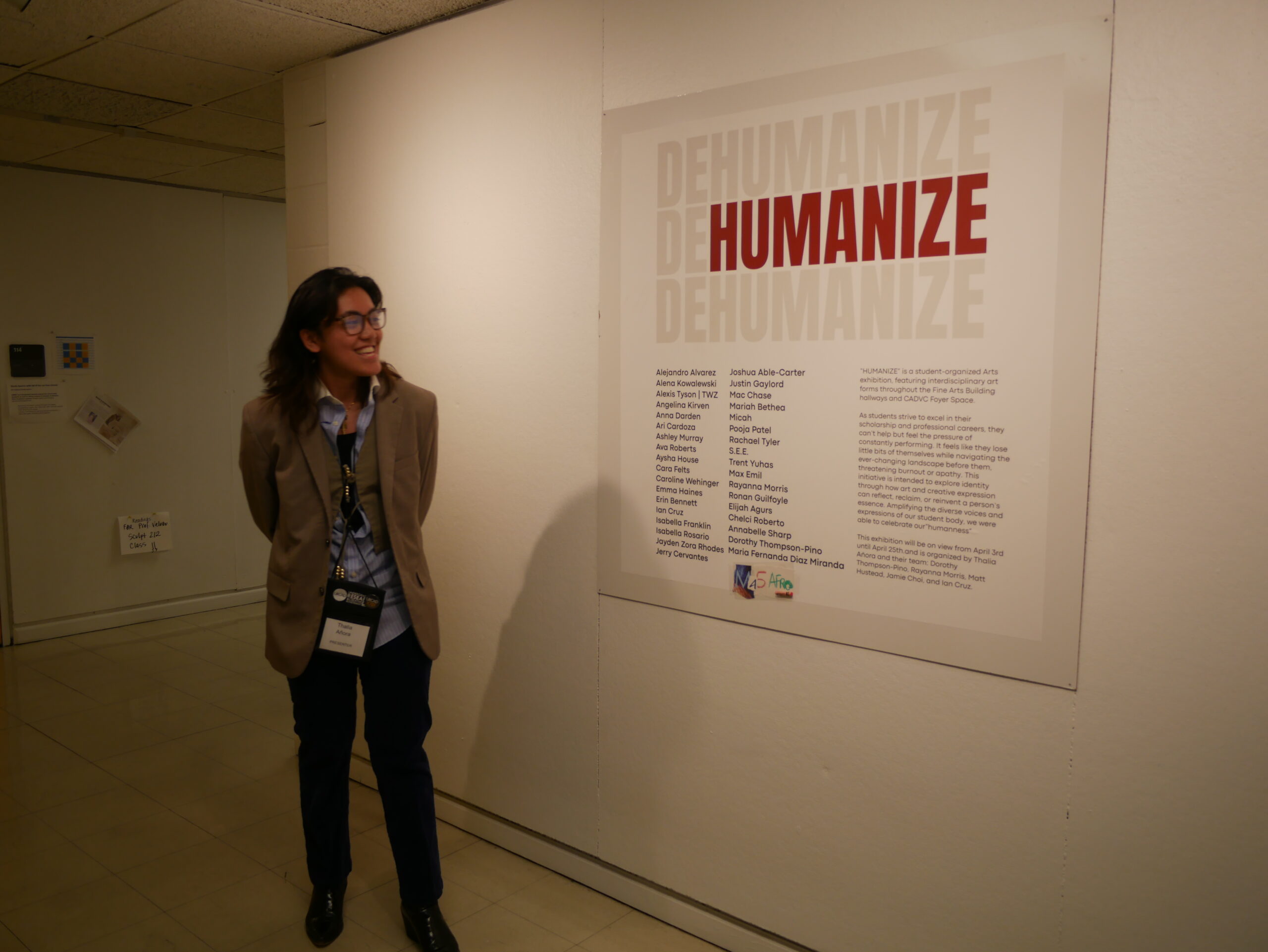 Thalia presenting while standing next to the Dehumanize sign