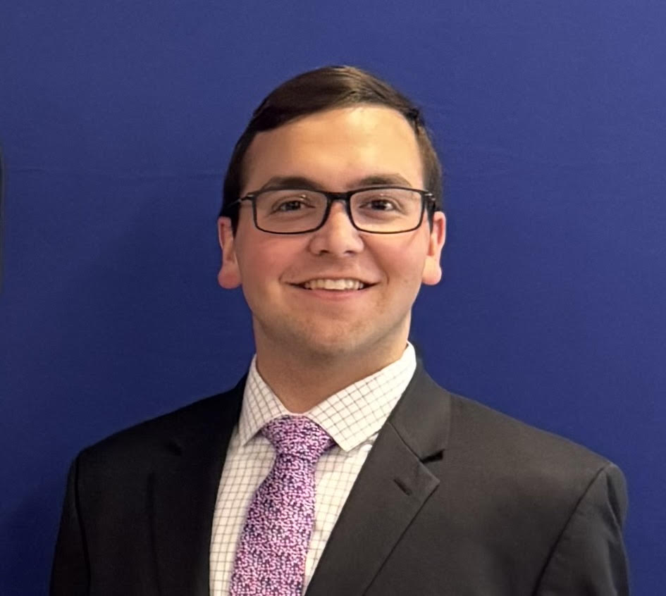 Paul smiling while standing in front of a blue background