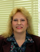 Dr. Vickie Williams smiling while standing behind white blinds